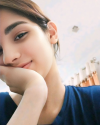 This may contain_ a woman with her hand on her chin looking at the camera
